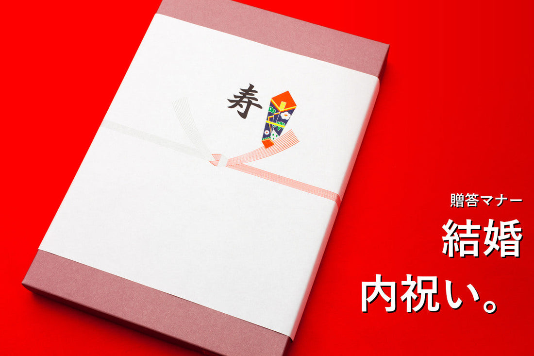 赤い背景に置かれた、寿ののし紙を掛けた結婚内祝いの贈り物