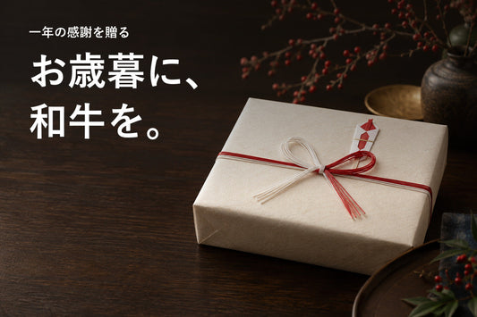暗い木の卓上に置いた紅白の水引付きの贈答箱と「お歳暮に、和牛を。」の見出し